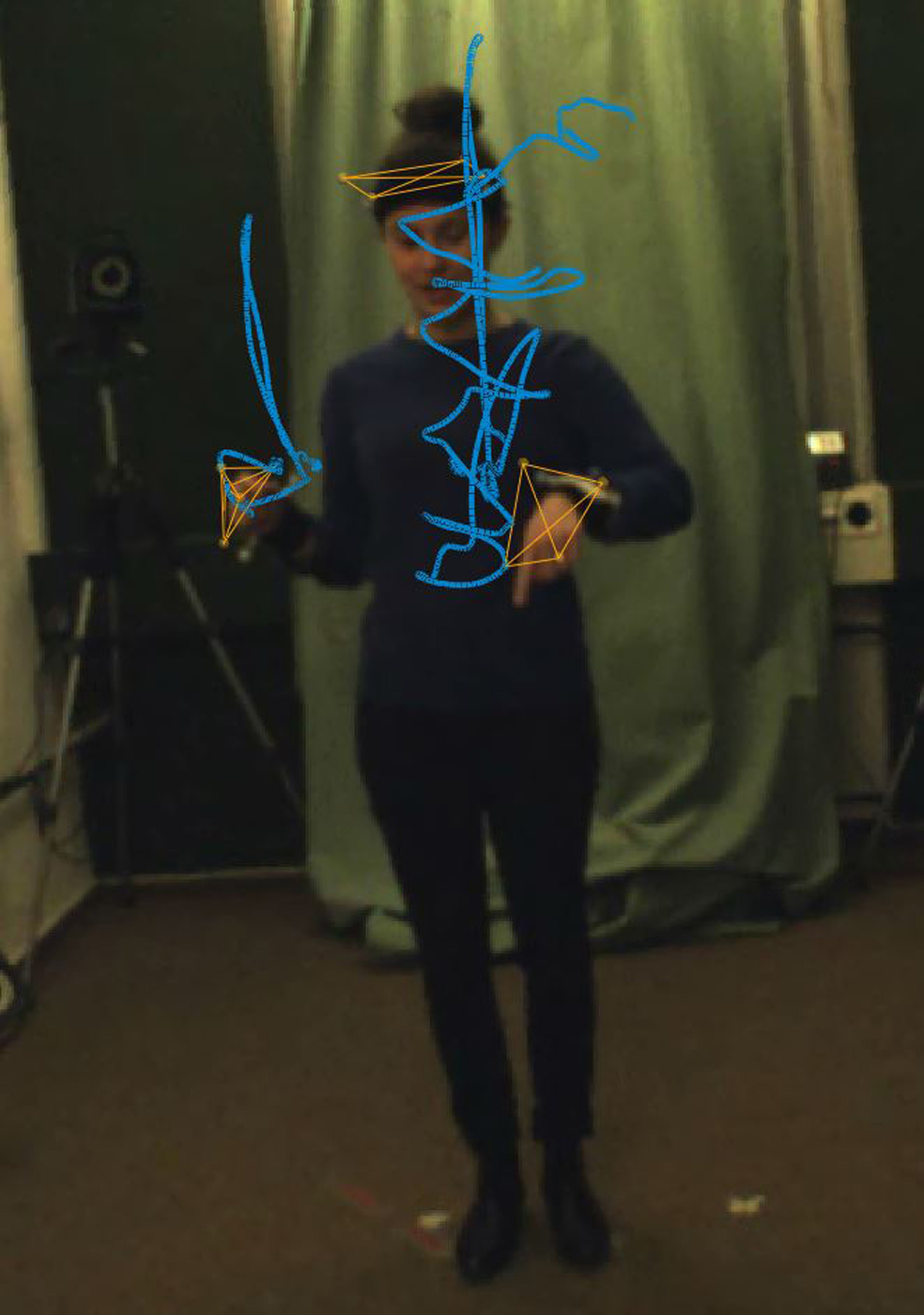 Frau steh in einem Labor und wird beim Gestikulieren aufgezeichnet. Ein Computergrafik-Overlay macht eine Spur ihrer Handbewegungen sichtbar.